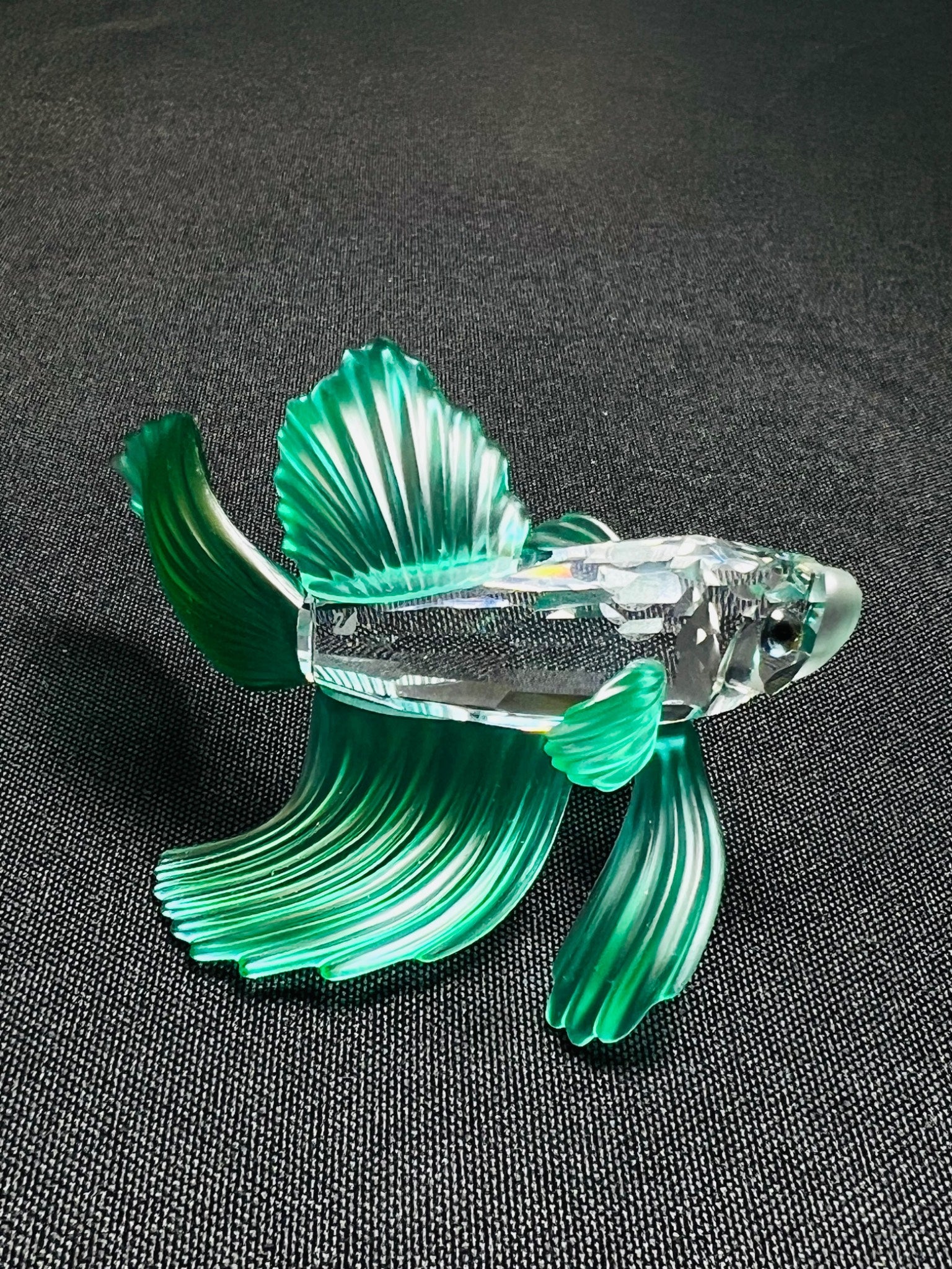 Glass fish figurine on a dark textured surface