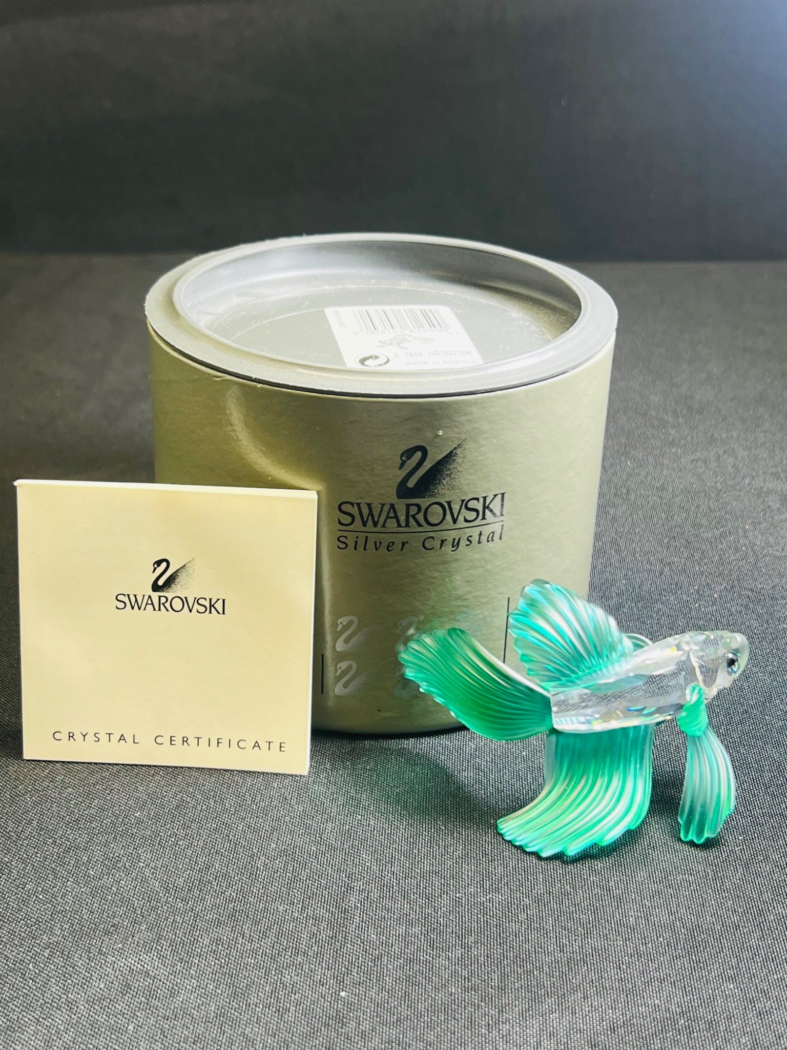 Swarovski crystal fish figurine with packaging and certificate on a gray surface