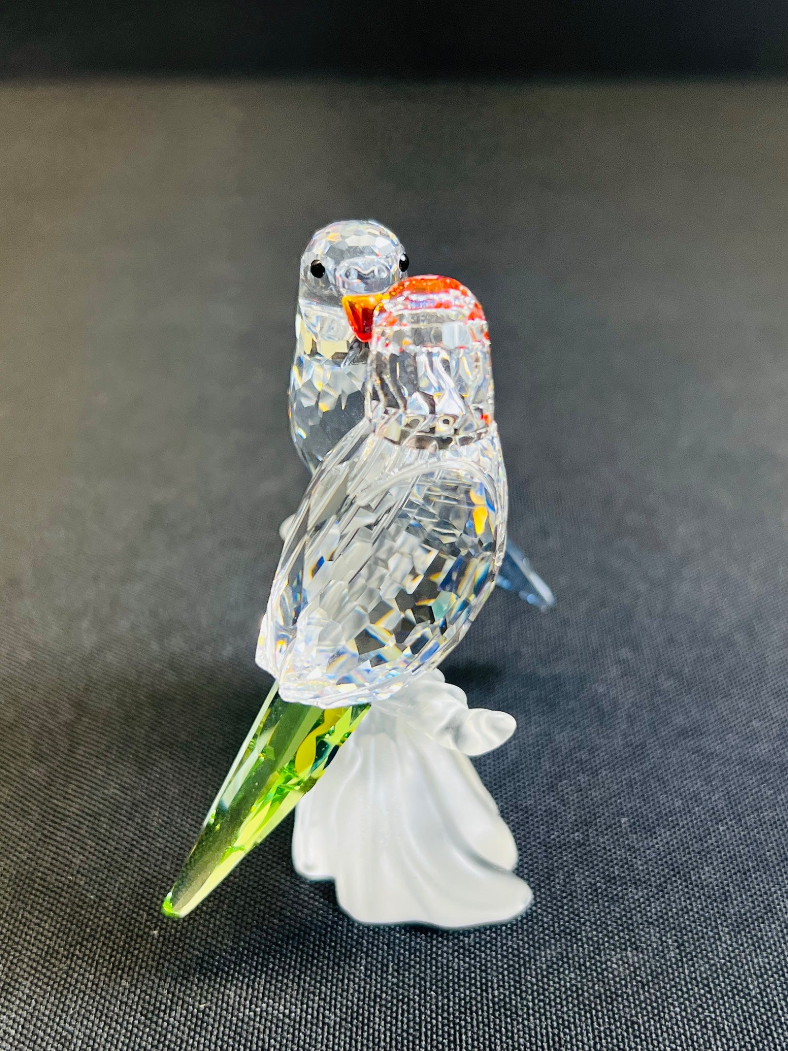 Glass parrot figurine on a dark textured surface