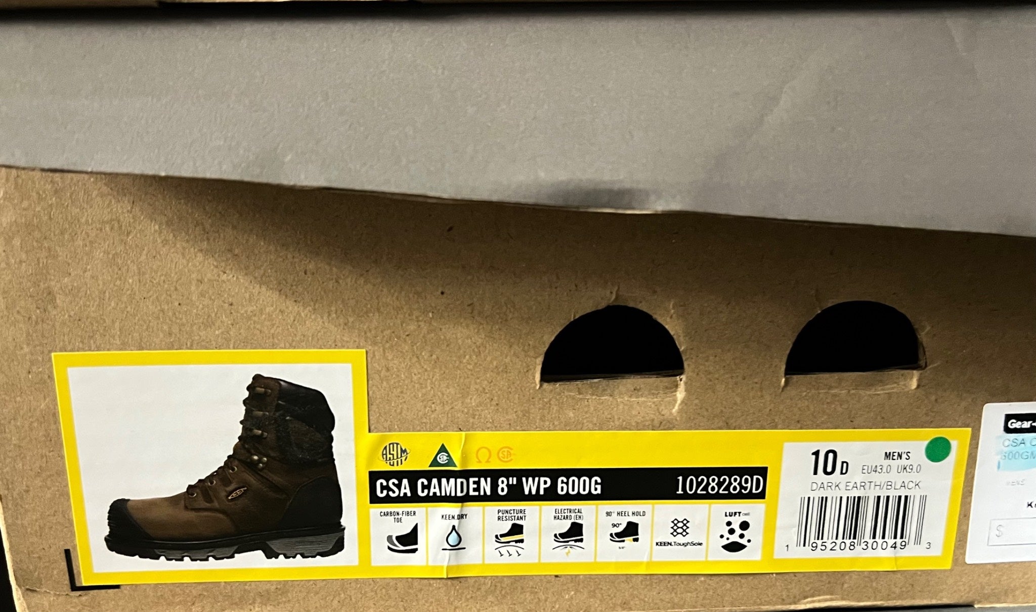 Cardboard box with a label featuring a boot and safety certification details.