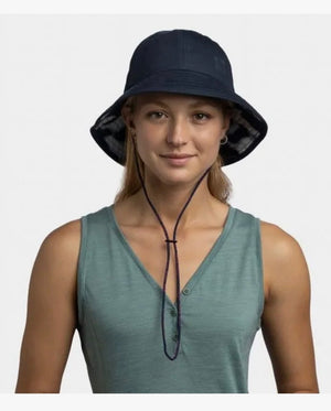 Woman wearing a navy bucket hat and green sleeveless top on a white background