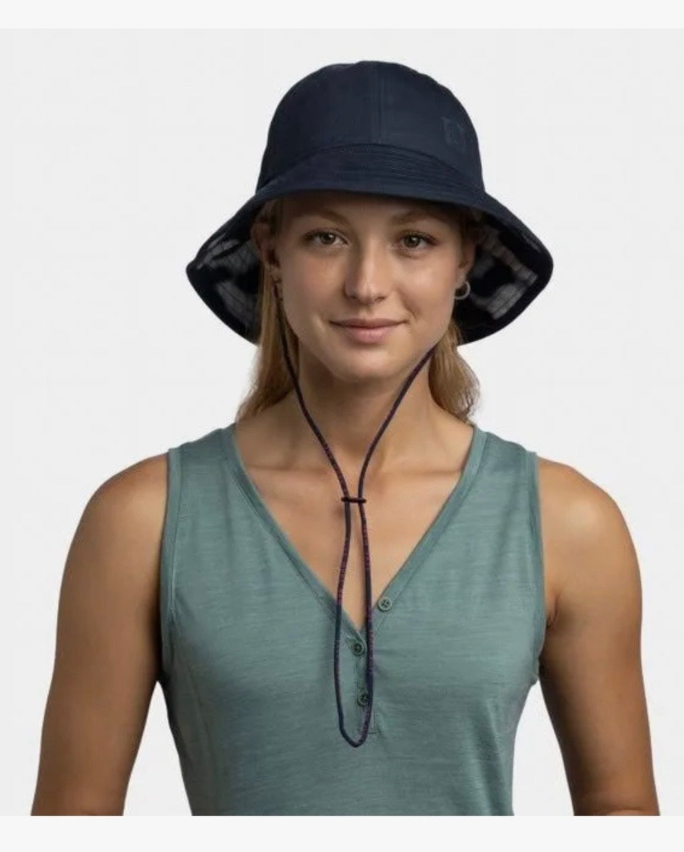 Woman wearing a navy bucket hat and green sleeveless top on a white background