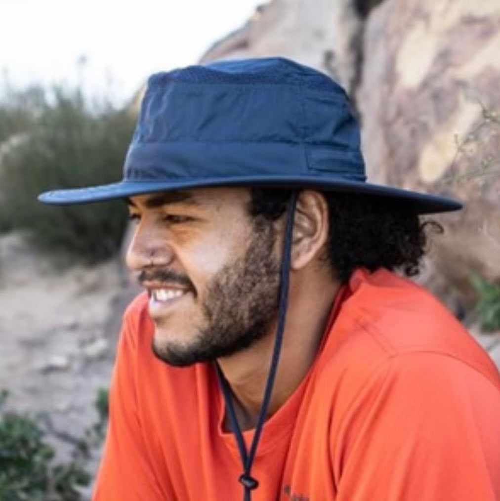 Man wearing a blue bucket hat outdoors with a natural background