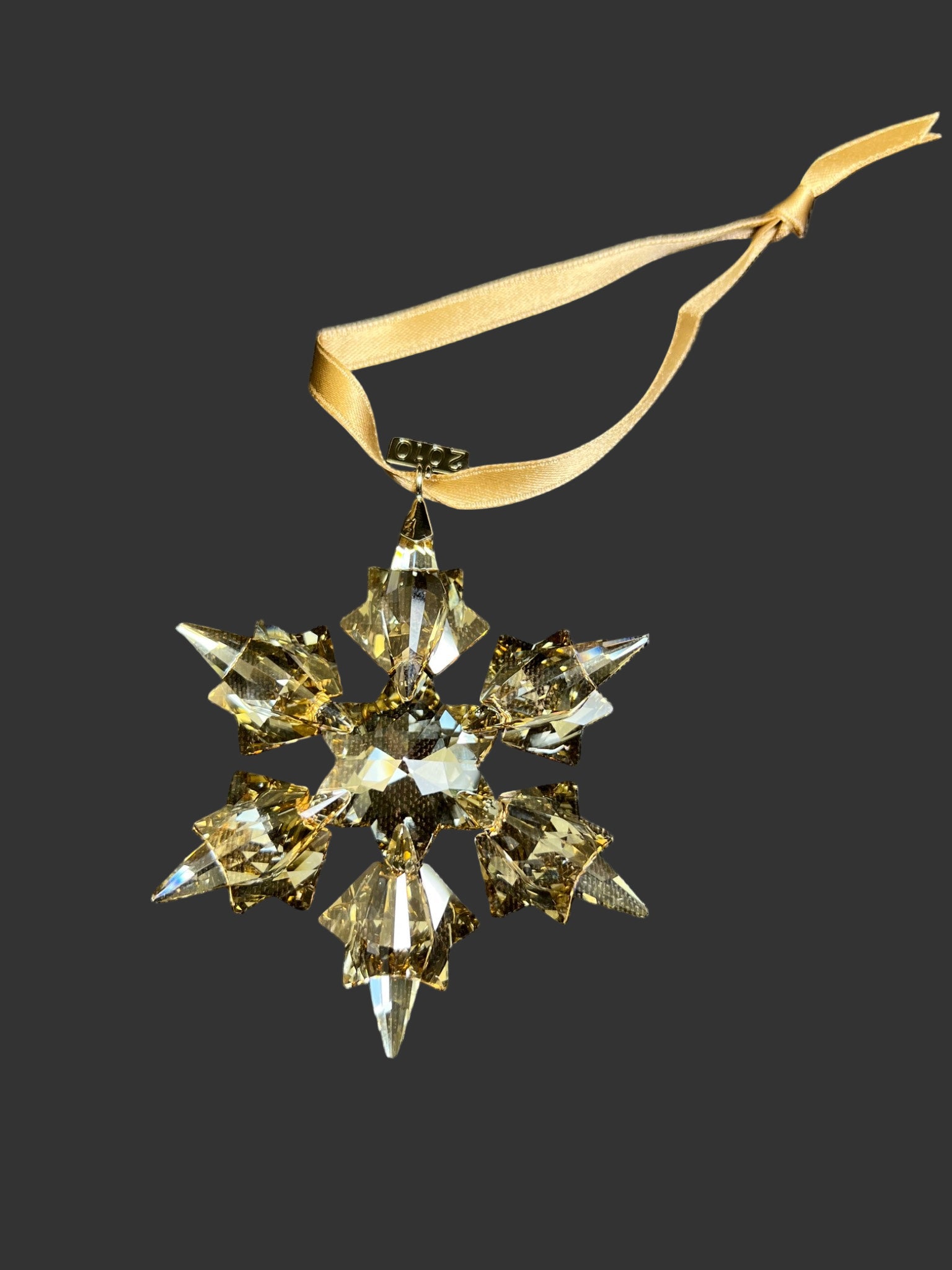 Crystal snowflake ornament with gold ribbon on a black background