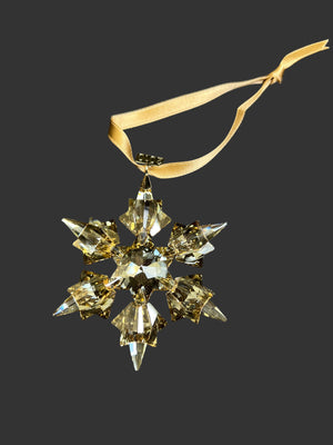 Crystal snowflake ornament with gold ribbon on a black background