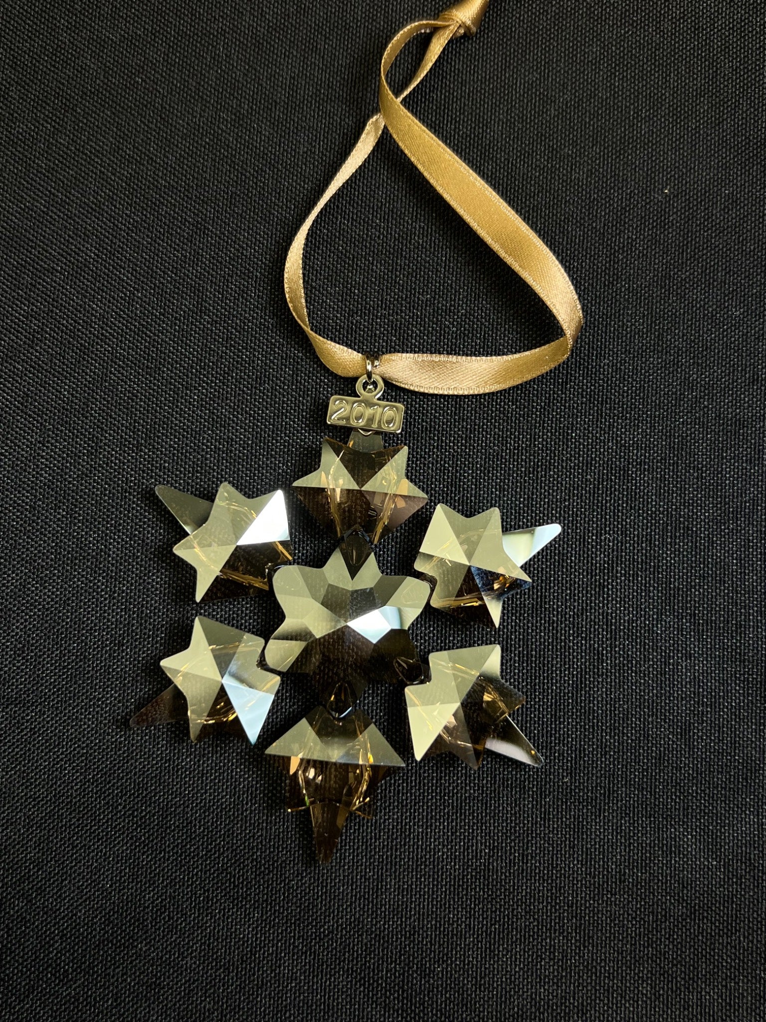 Decorative gold star ornament with a ribbon on a black background