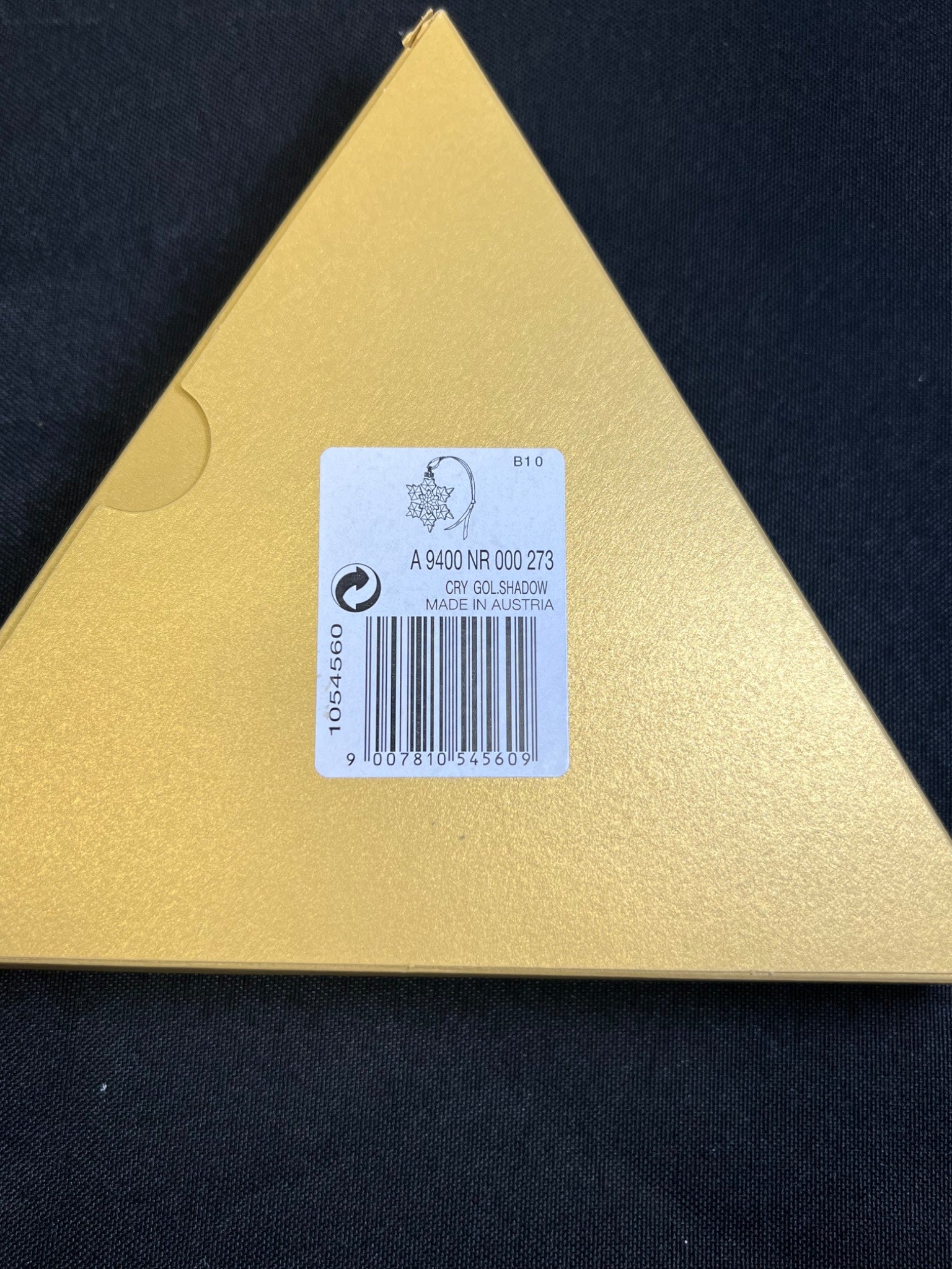 Triangular gold object with a label on a black background