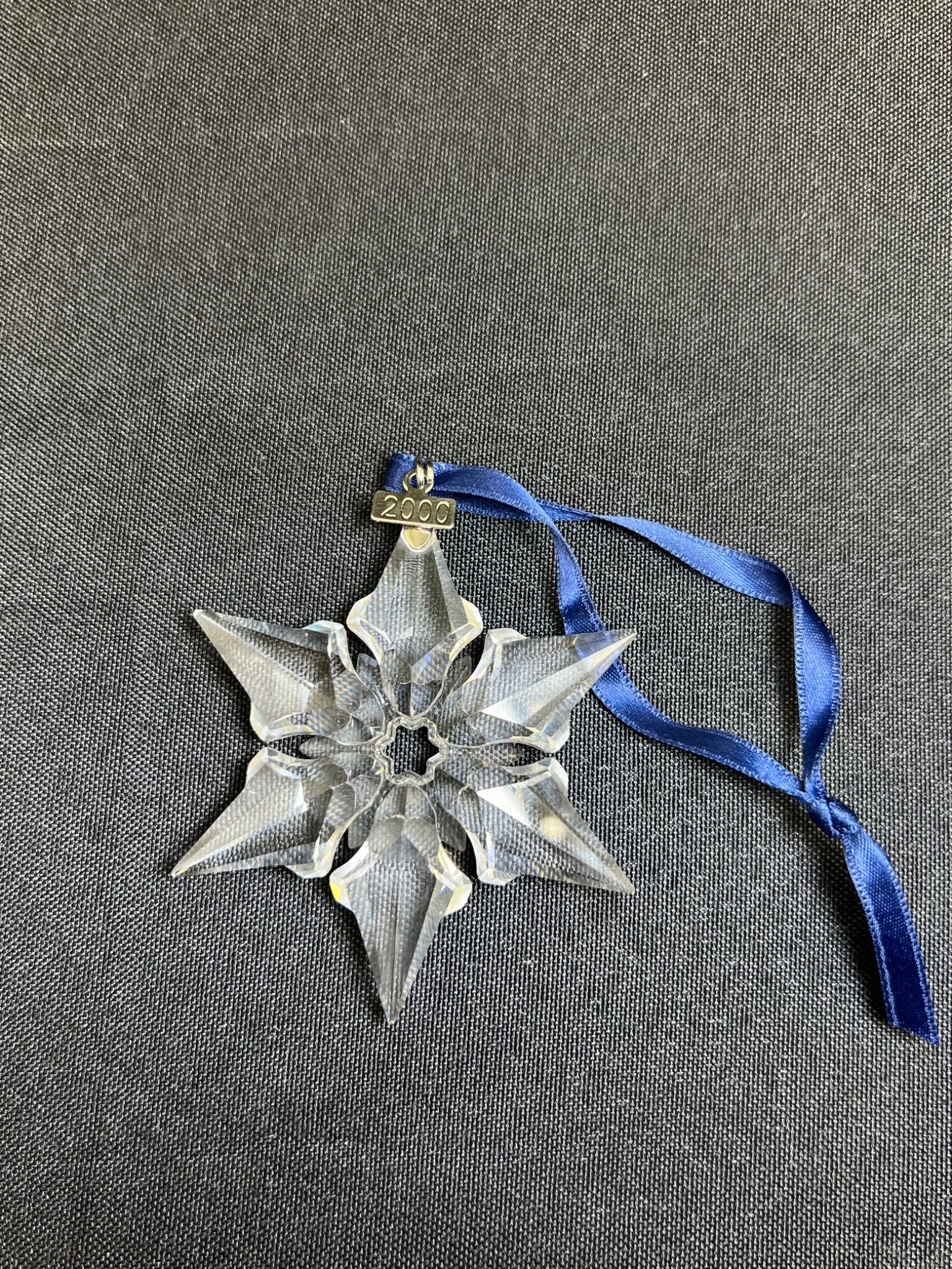 Decorative star ornament with blue ribbon on a gray background