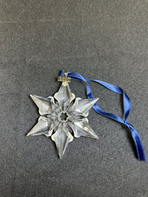 Decorative star ornament with blue ribbon on a gray background