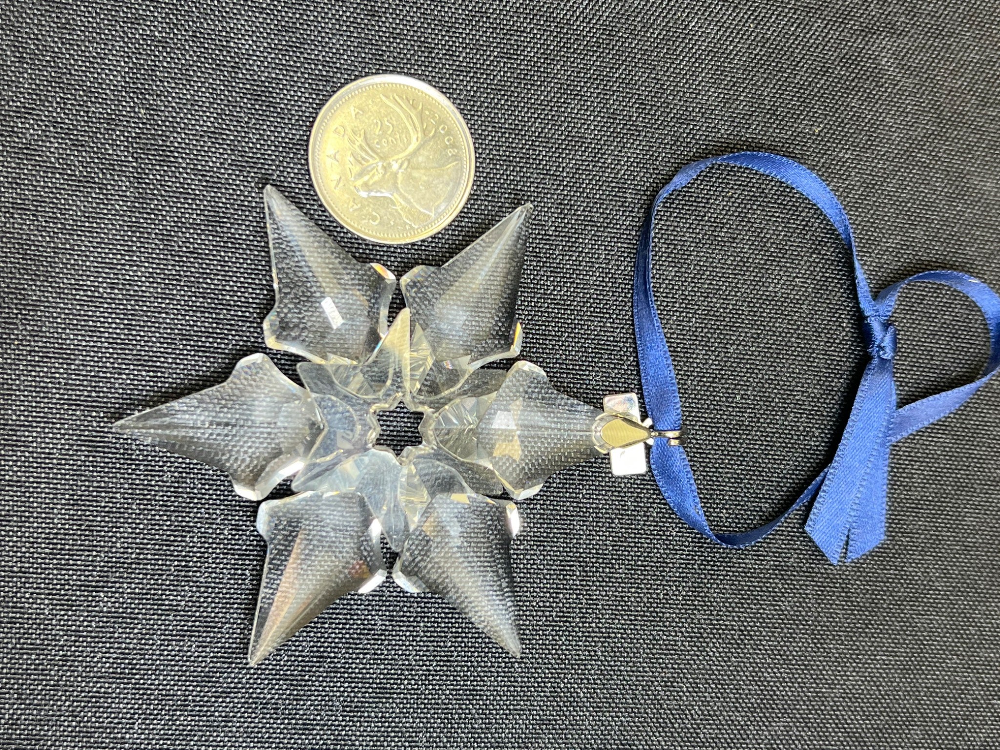 Decorative star-shaped object with a blue ribbon on a textured gray background