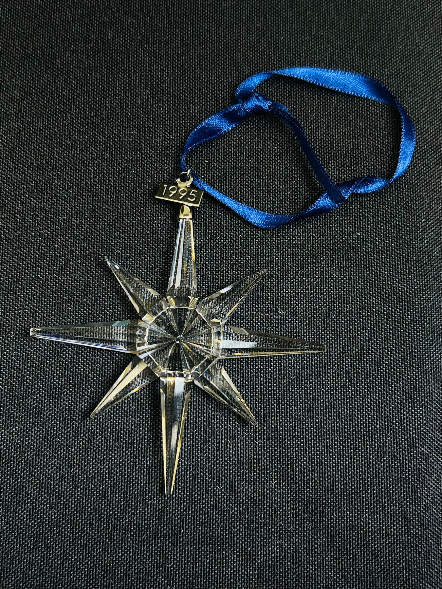 Decorative star ornament with blue ribbon on a black background