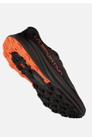 Black sports shoe with orange sole on a white background