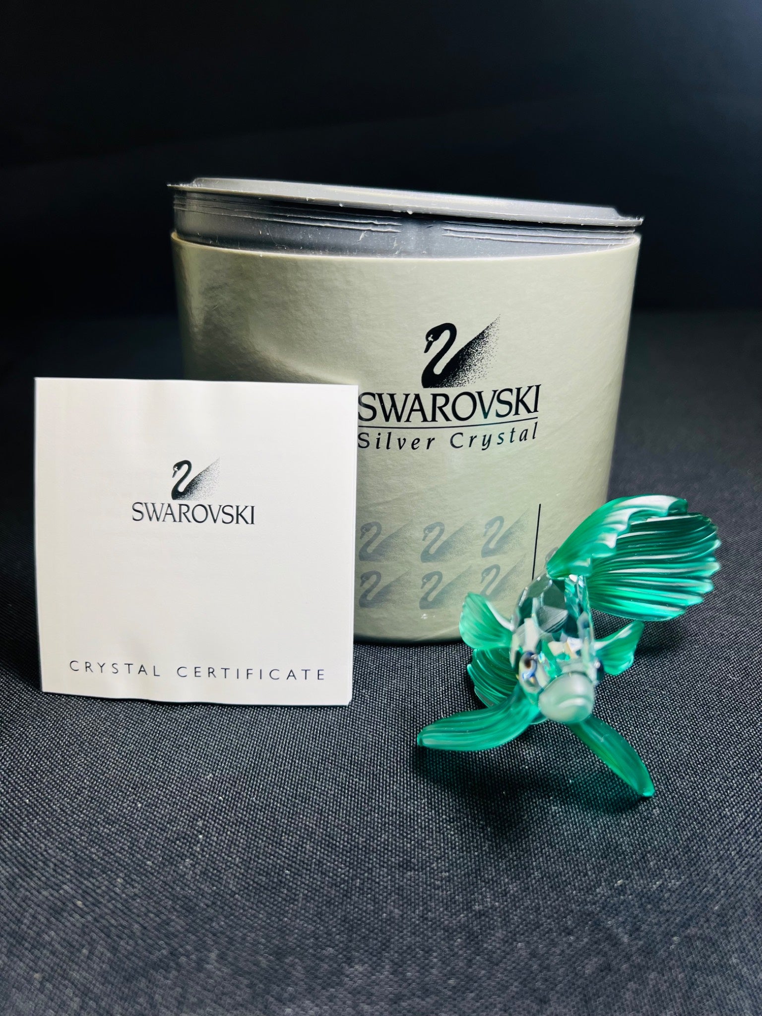 Swarovski crystal brooch with packaging and certificate on a dark surface