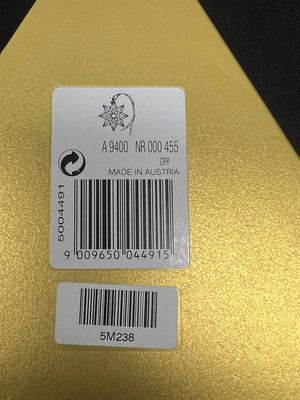 Two barcode labels on a gold surface with text and symbols.