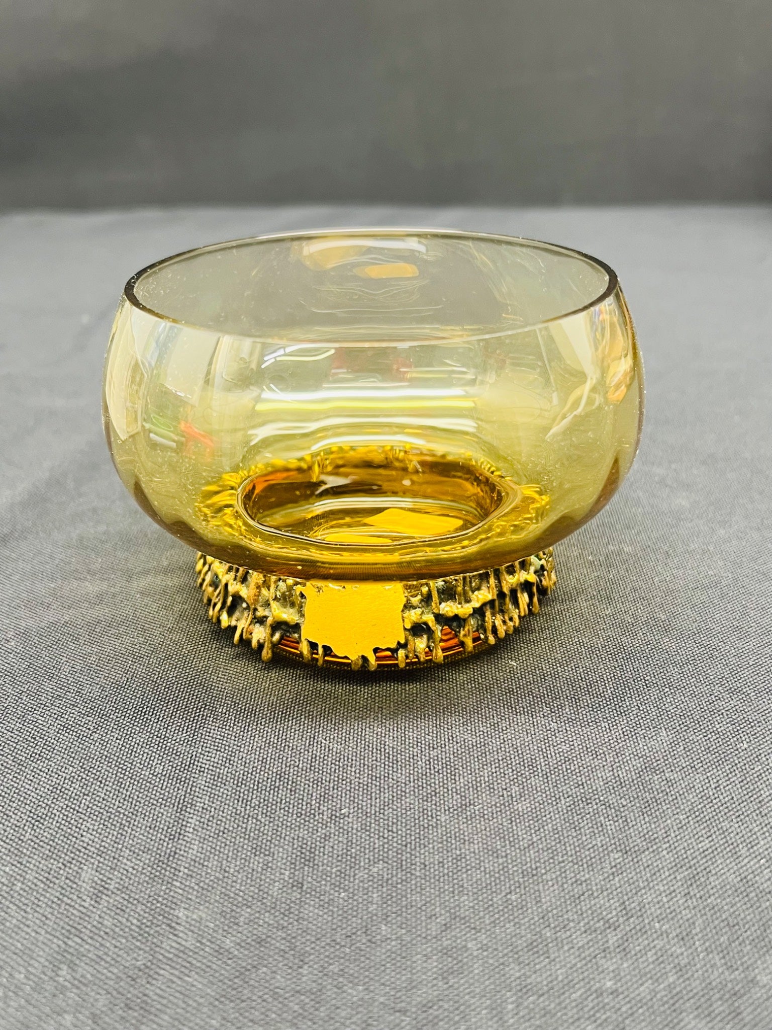 Amber glass bowl with decorative base on a gray surface