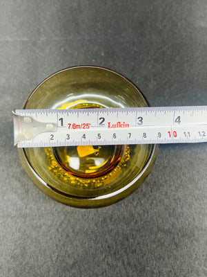 Measuring a round metallic object with a ruler on a gray background