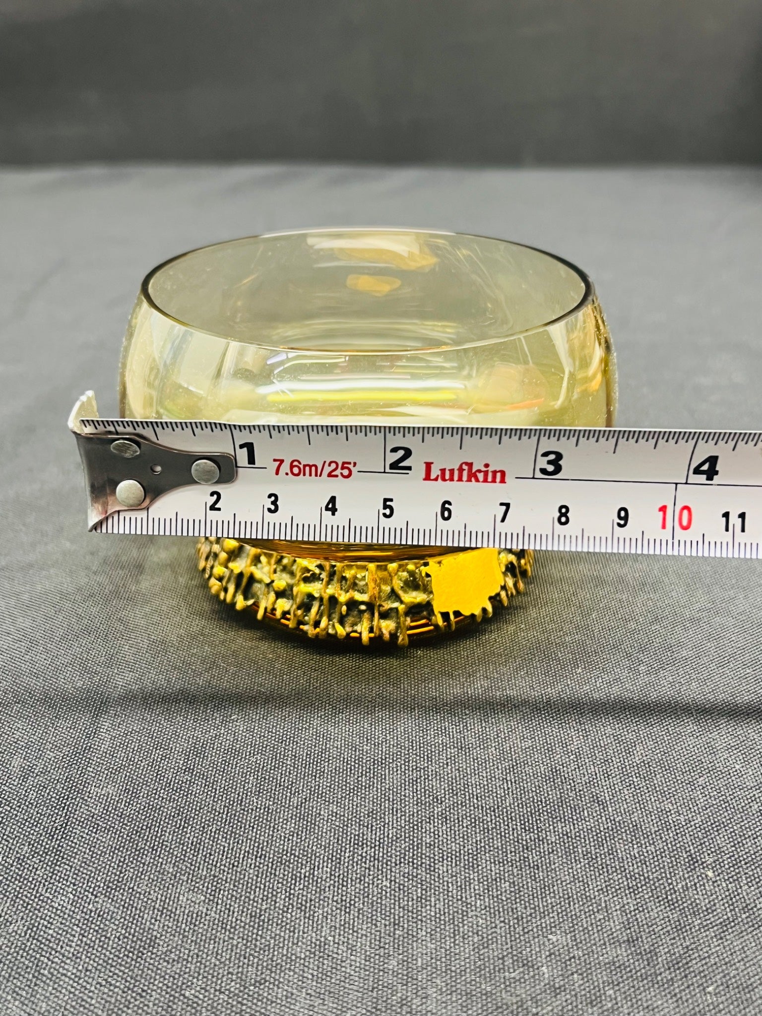 Yellow glass object with a ruler for scale on a gray background