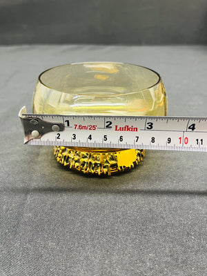 Yellow glass object with a ruler for scale on a gray background