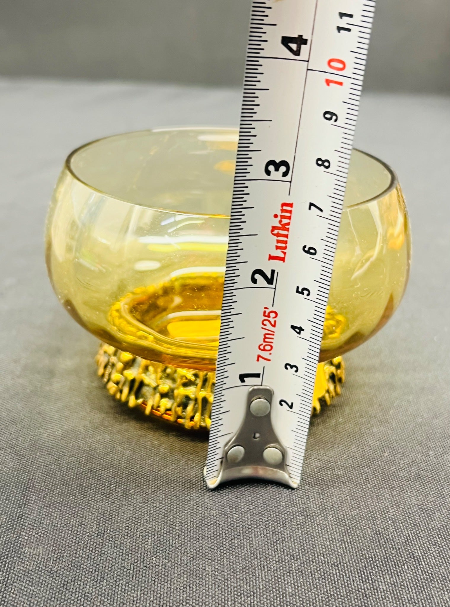 Yellow glass bowl with a ruler for scale on a gray background