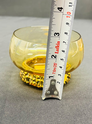 Yellow glass bowl with a ruler for scale on a gray background