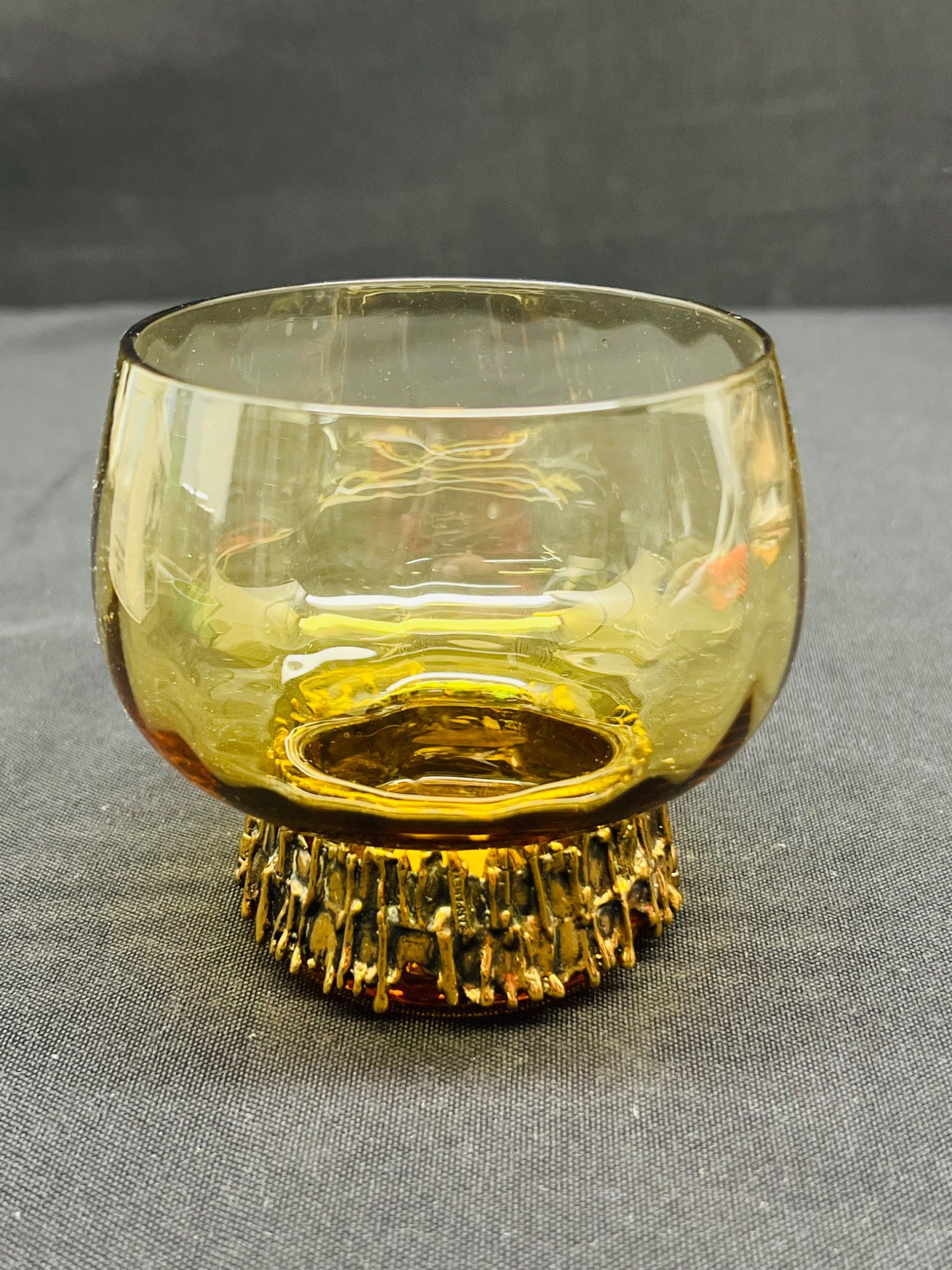 Amber glass candle holder with textured base on a gray surface