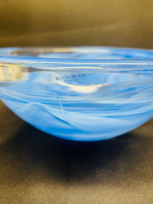 Blue glass bowl with 'Kosta Boda' branding on a brown surface
