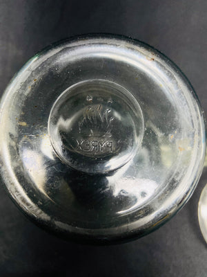 Close-up of a glass container lid with a brand logo on a dark background