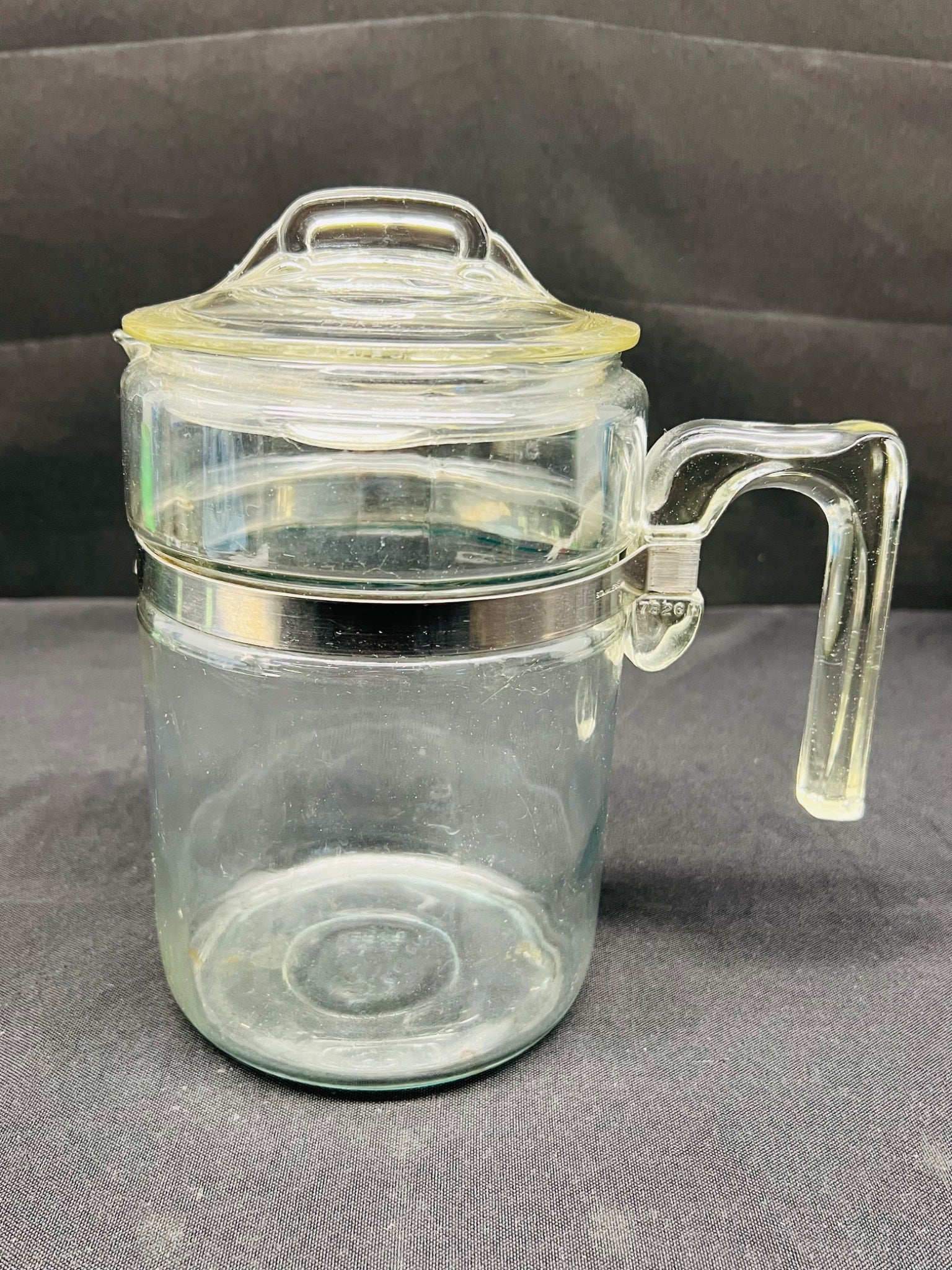 Clear glass jar with handle and lid on a gray background