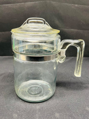 Clear glass jar with handle and lid on a gray background