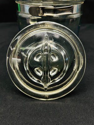 Clear glass jar with a decorative lid on a black background