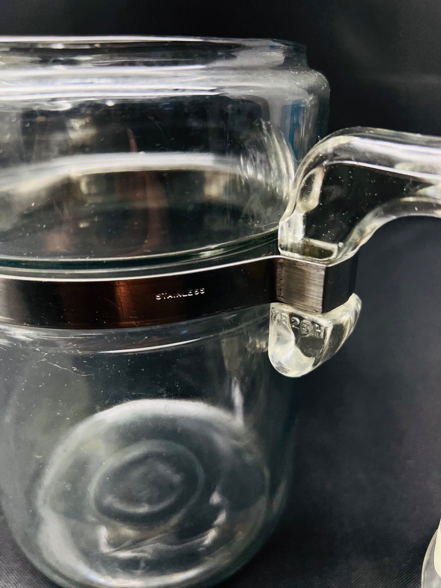 Clear glass container with a handle on a dark background