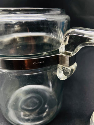 Clear glass container with a handle on a dark background