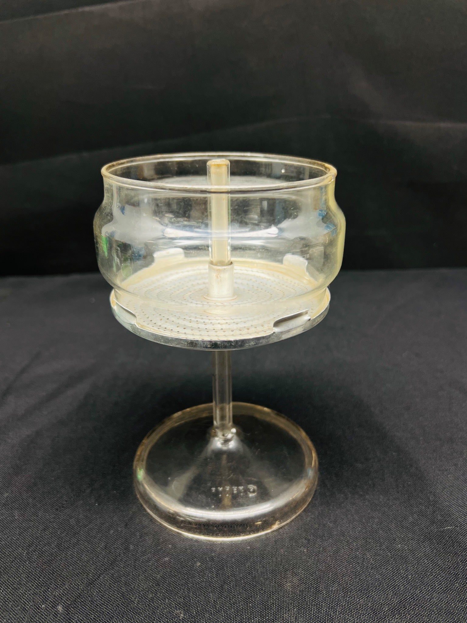 Clear glass object with a stand on a black background