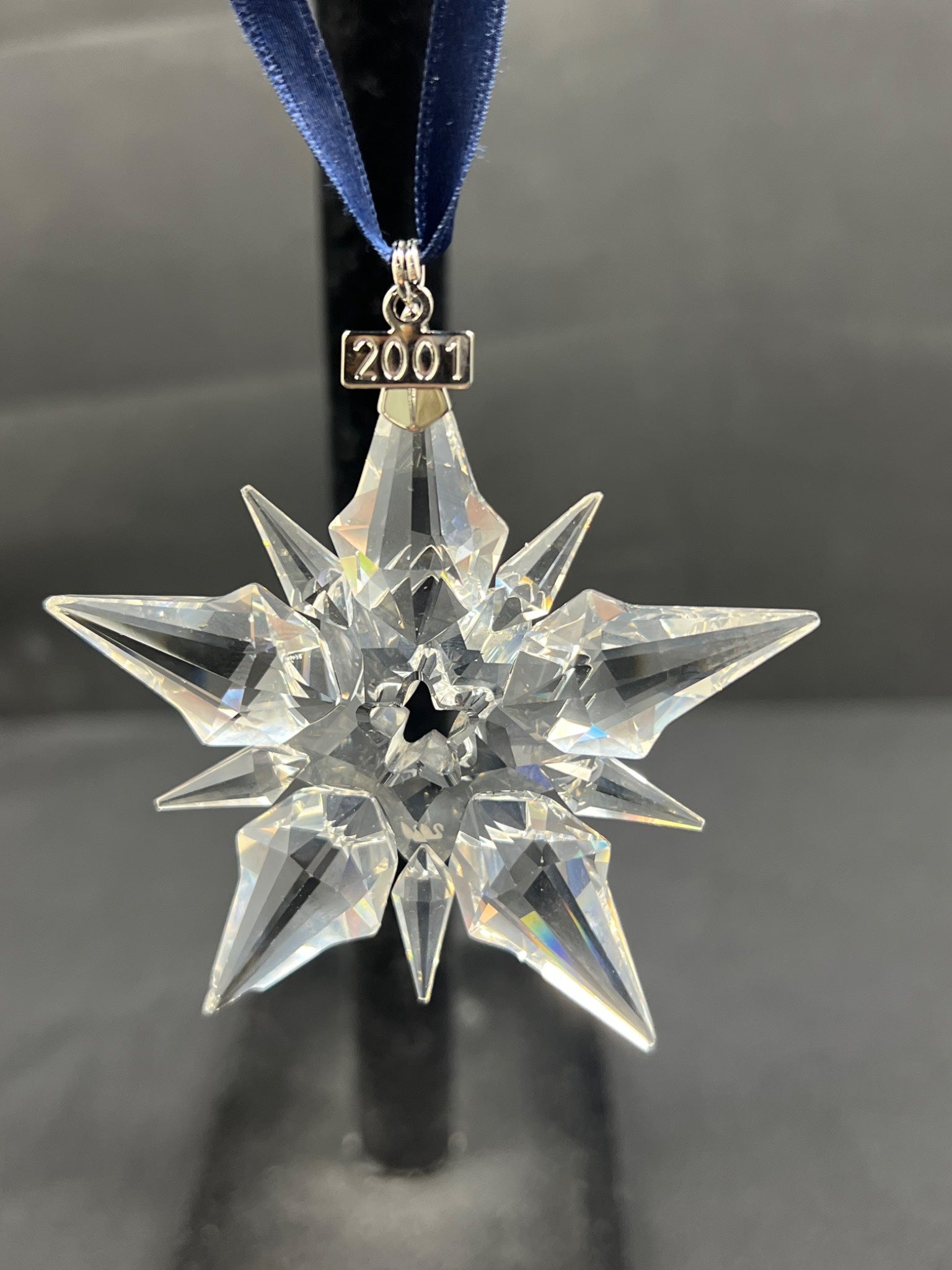Crystal star-shaped ornament with '2001' on a dark background