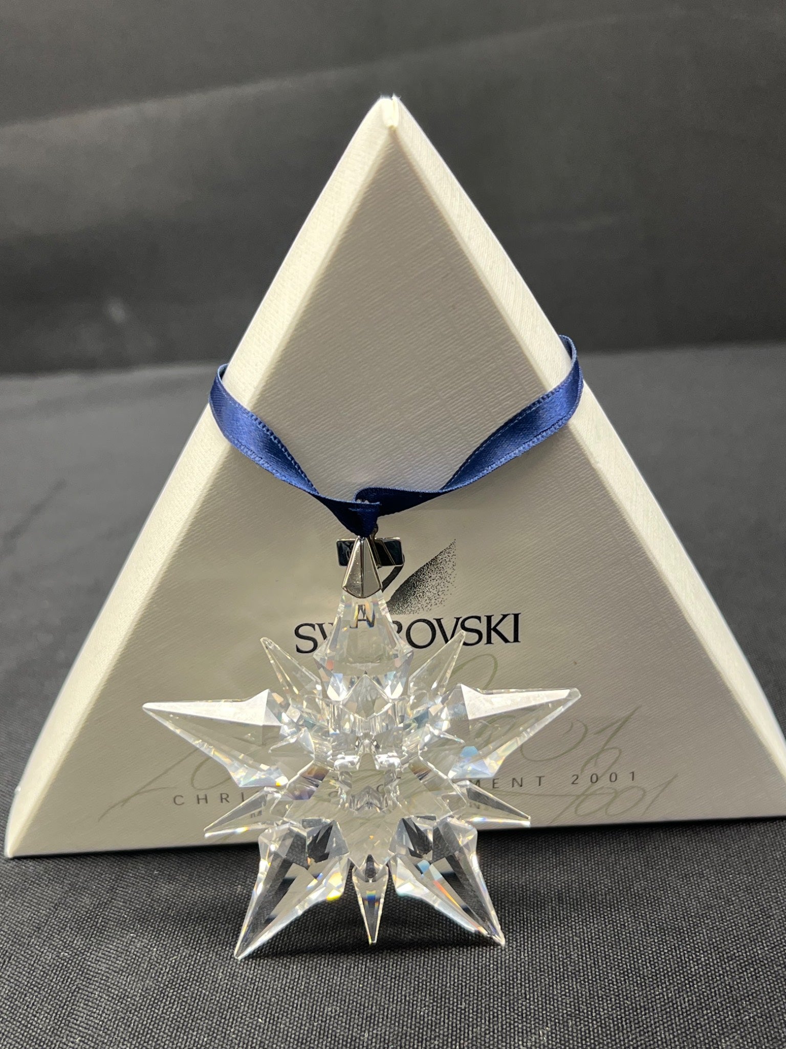 Crystal star ornament with Swarovski logo on a triangular display stand.