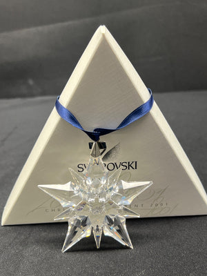 Crystal star ornament with Swarovski logo on a triangular display stand.