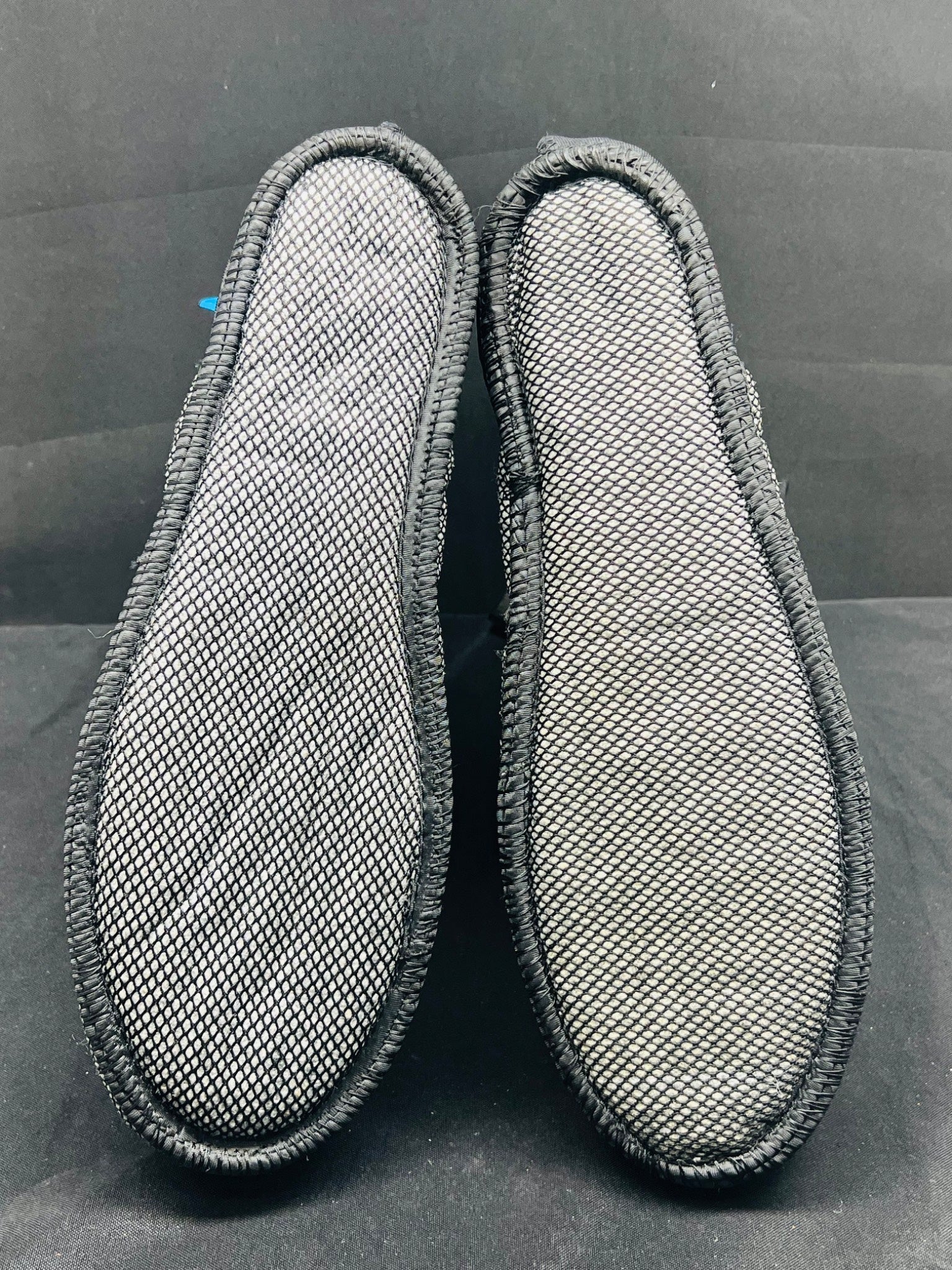 Pair of gray shoe inserts on a black background
