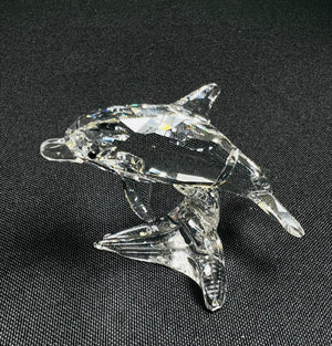Clear glass dolphin figurine on a black background
