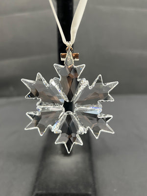 Clear snowflake-shaped ornament on a dark background