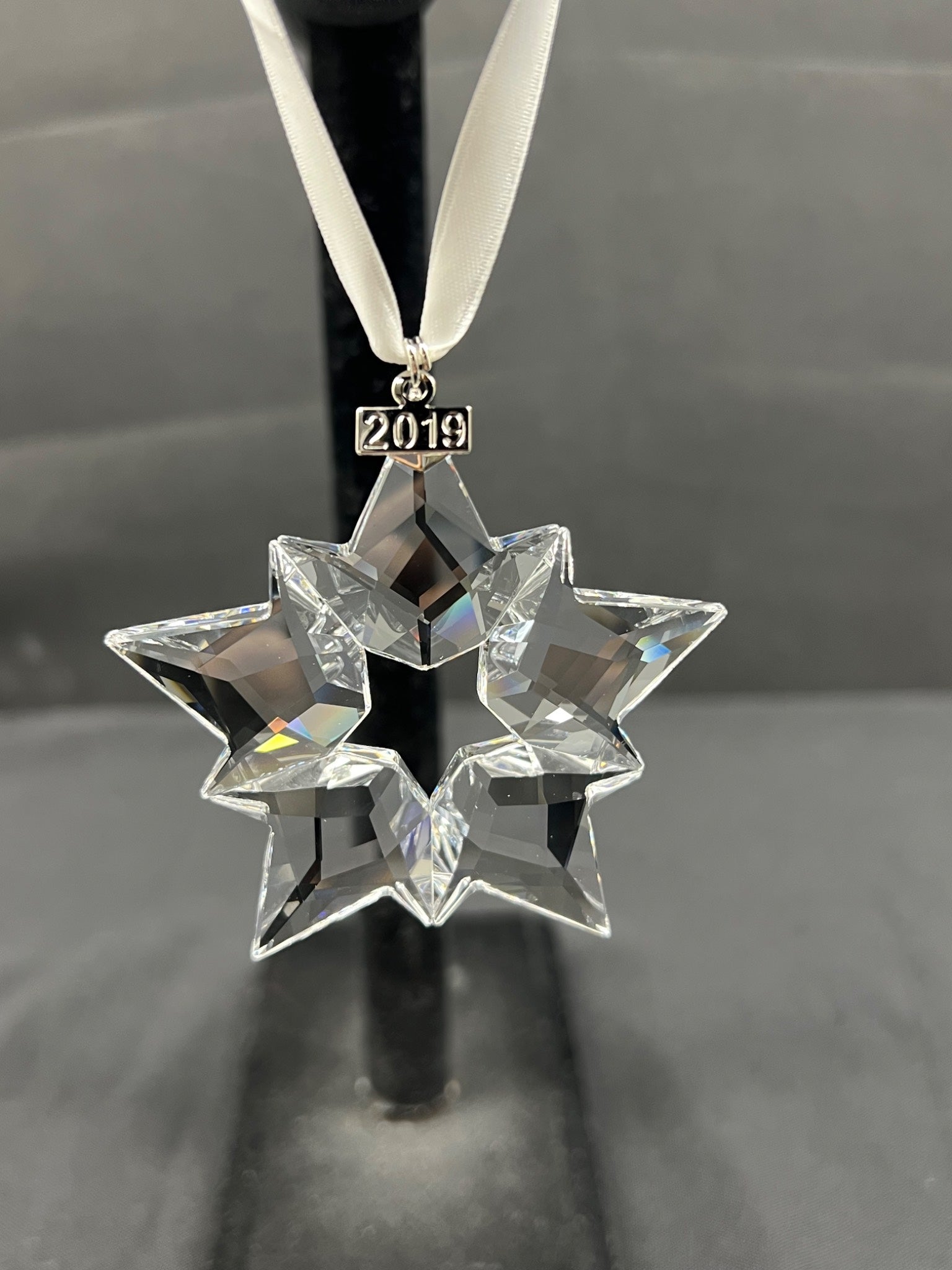 Crystal star ornament with '2019' on a black stand against a gray background