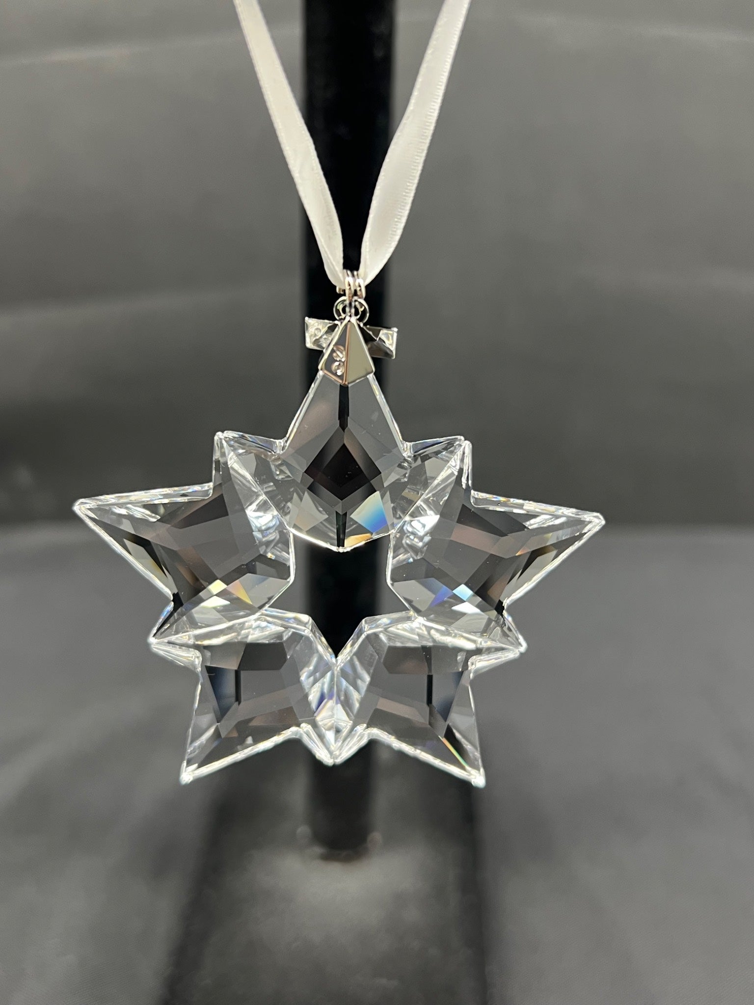Crystal star-shaped ornament on a black stand against a gray background