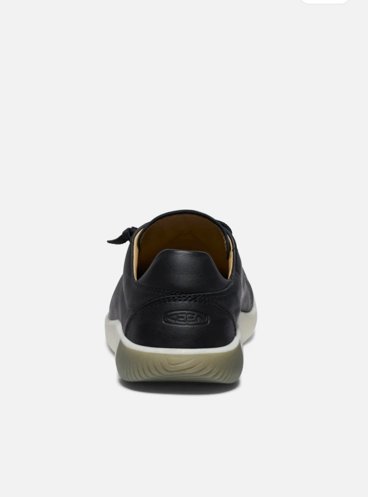 Black leather shoe with white sole on a light gray background