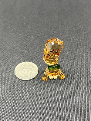 Small glass figurine of a lion with a coin for scale on a gray background