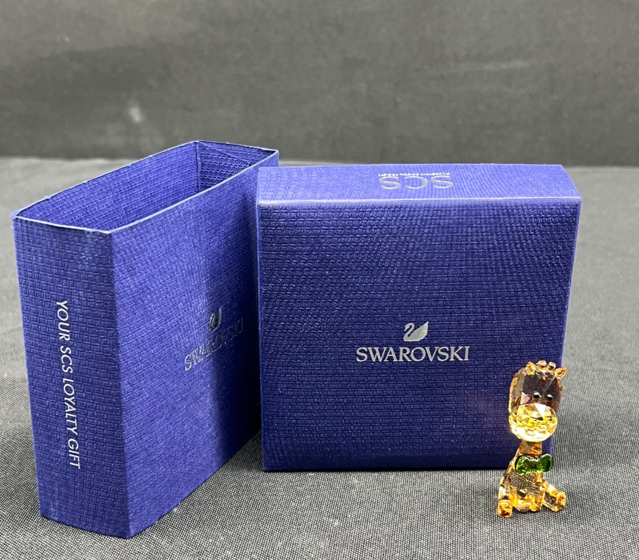 Swarovski crystal figure next to a blue Swarovski box on a gray surface