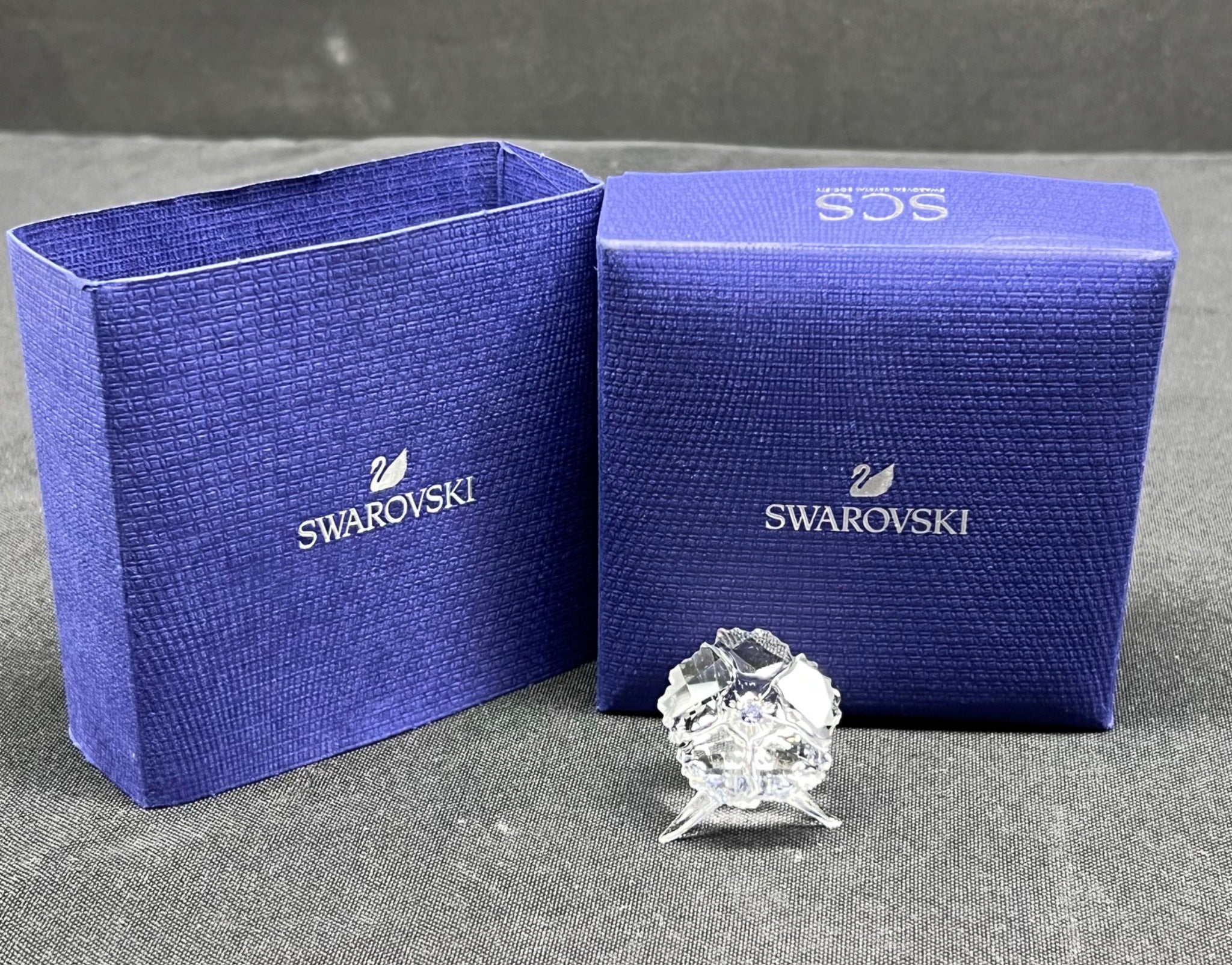Swarovski crystal figurine with two blue Swarovski boxes on a gray surface