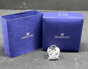 Swarovski crystal figurine with two blue Swarovski boxes on a gray surface