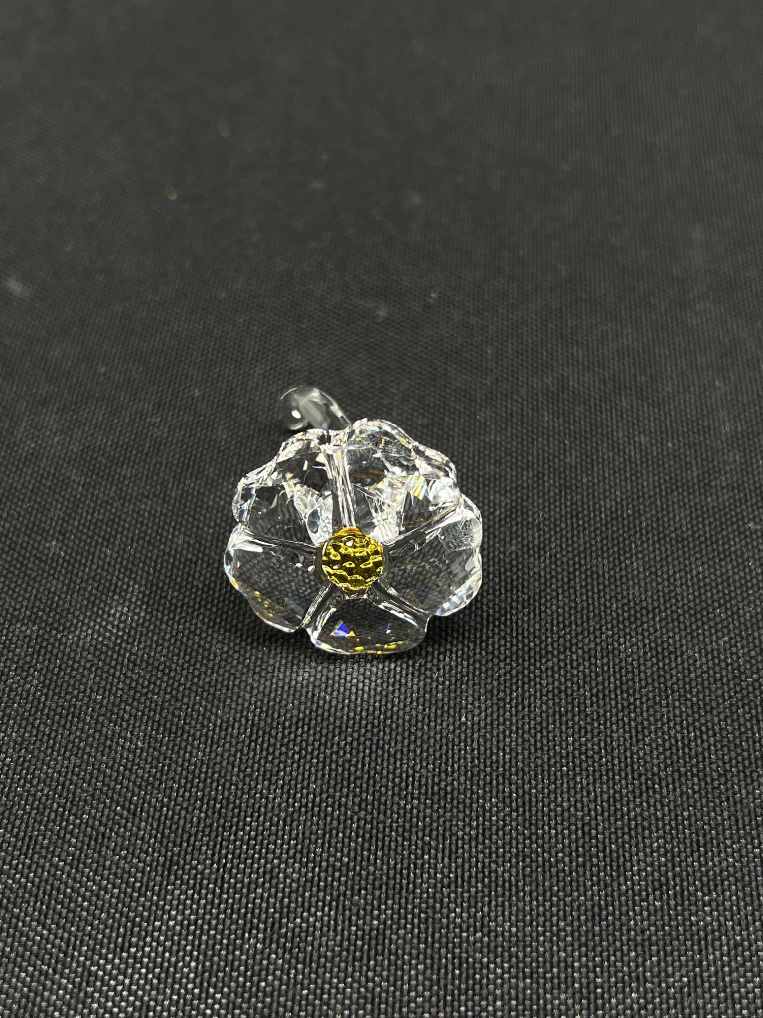 Clear glass flower with yellow center on a black background
