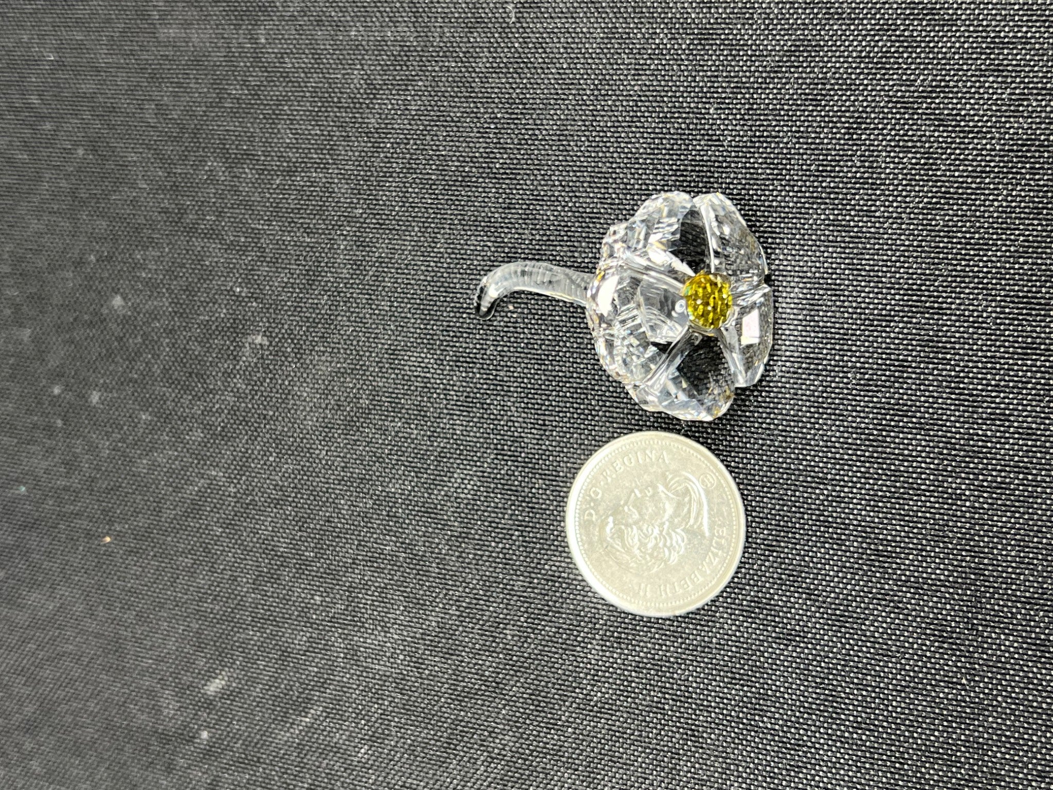 Clear glass flower with yellow center on a dark textured background