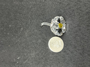 Clear glass flower with yellow center on a dark textured background