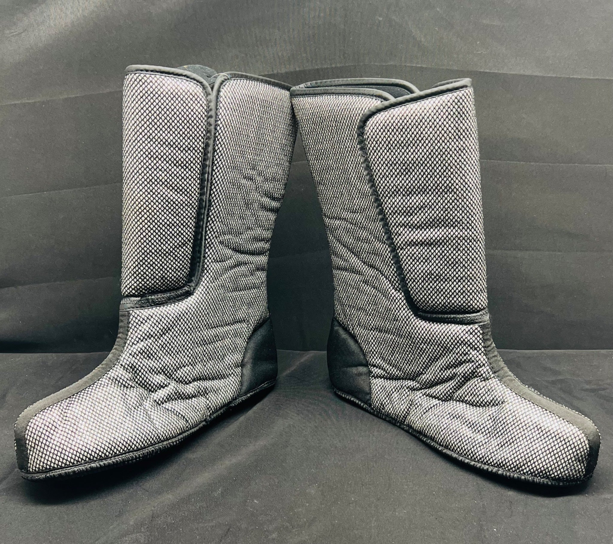 Pair of gray quilted knee-high boots on a gray background